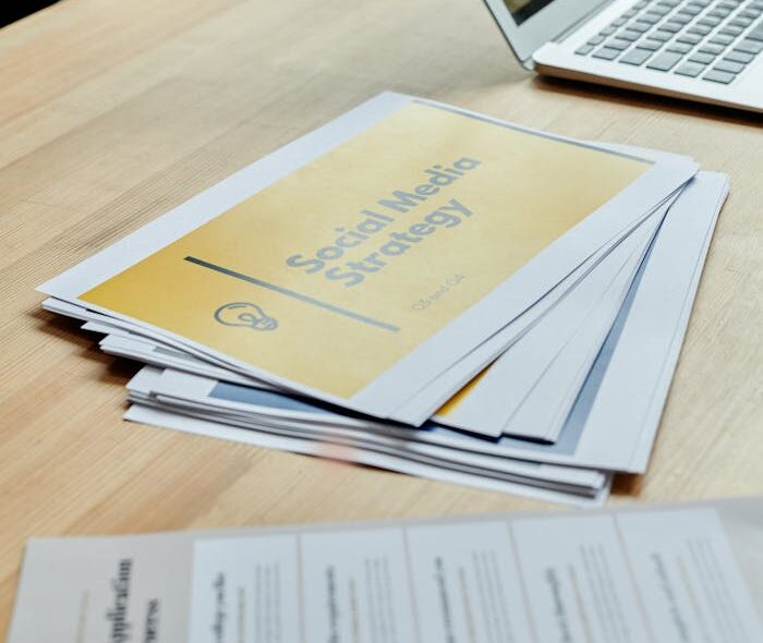 Close-up of social media strategy documents on a desk with a laptop, highlighting office planning.